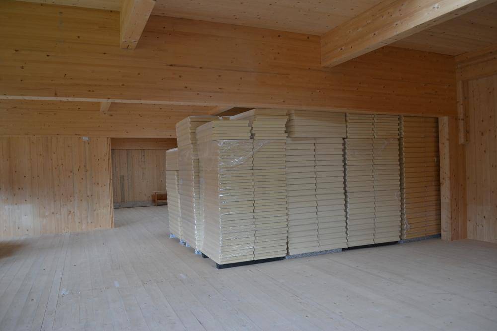 Großer Lagerraum mit Holzverkleidung, Holzbalken und hohen Stapeln von Dämmplatten.