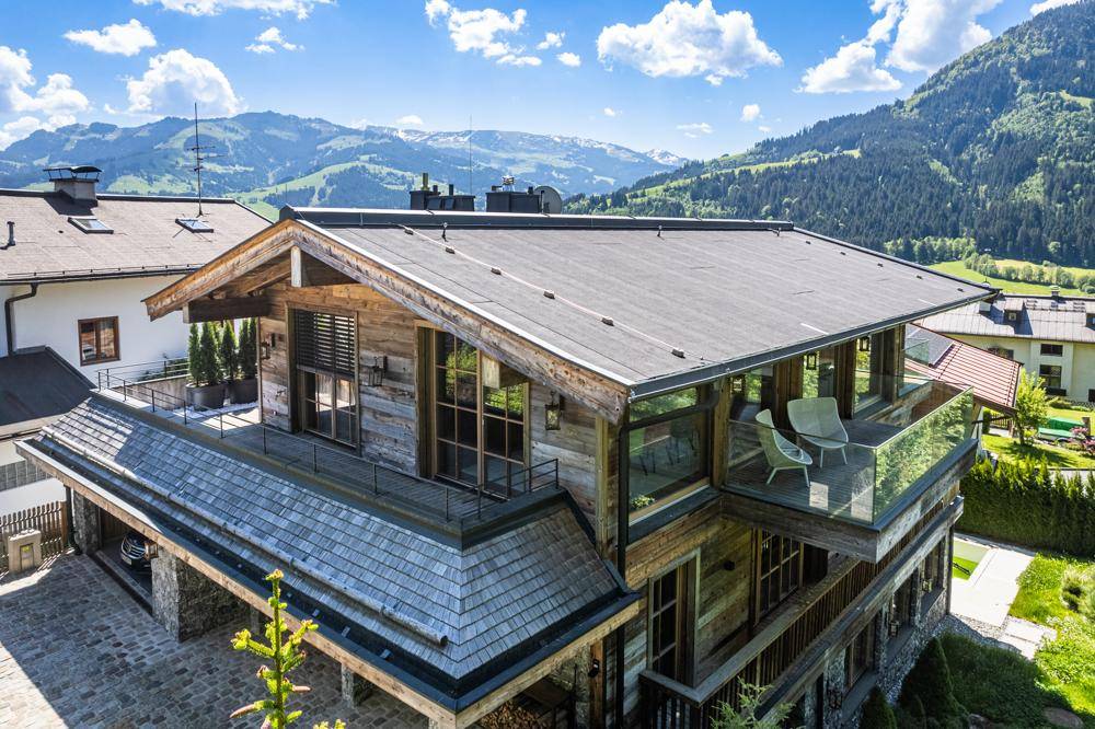 Panoramablick auf das luxuriöse Chalet mit seinen Terrassen und der umliegenden Berglandschaft.
