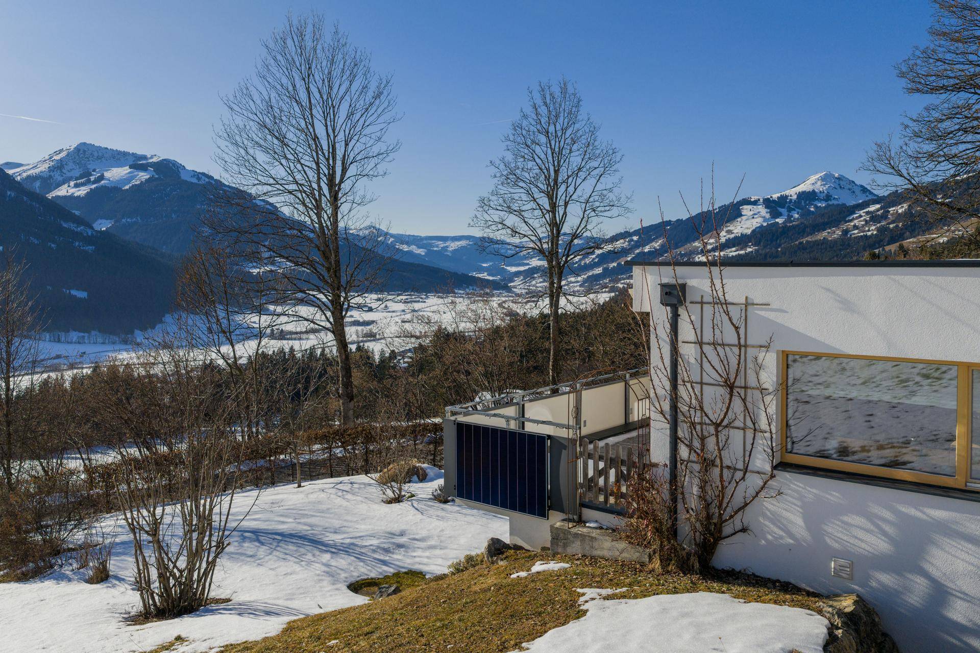 Teilansicht des Hauses mit weitem Blick über das verschneite Tal und die umliegenden Berge.