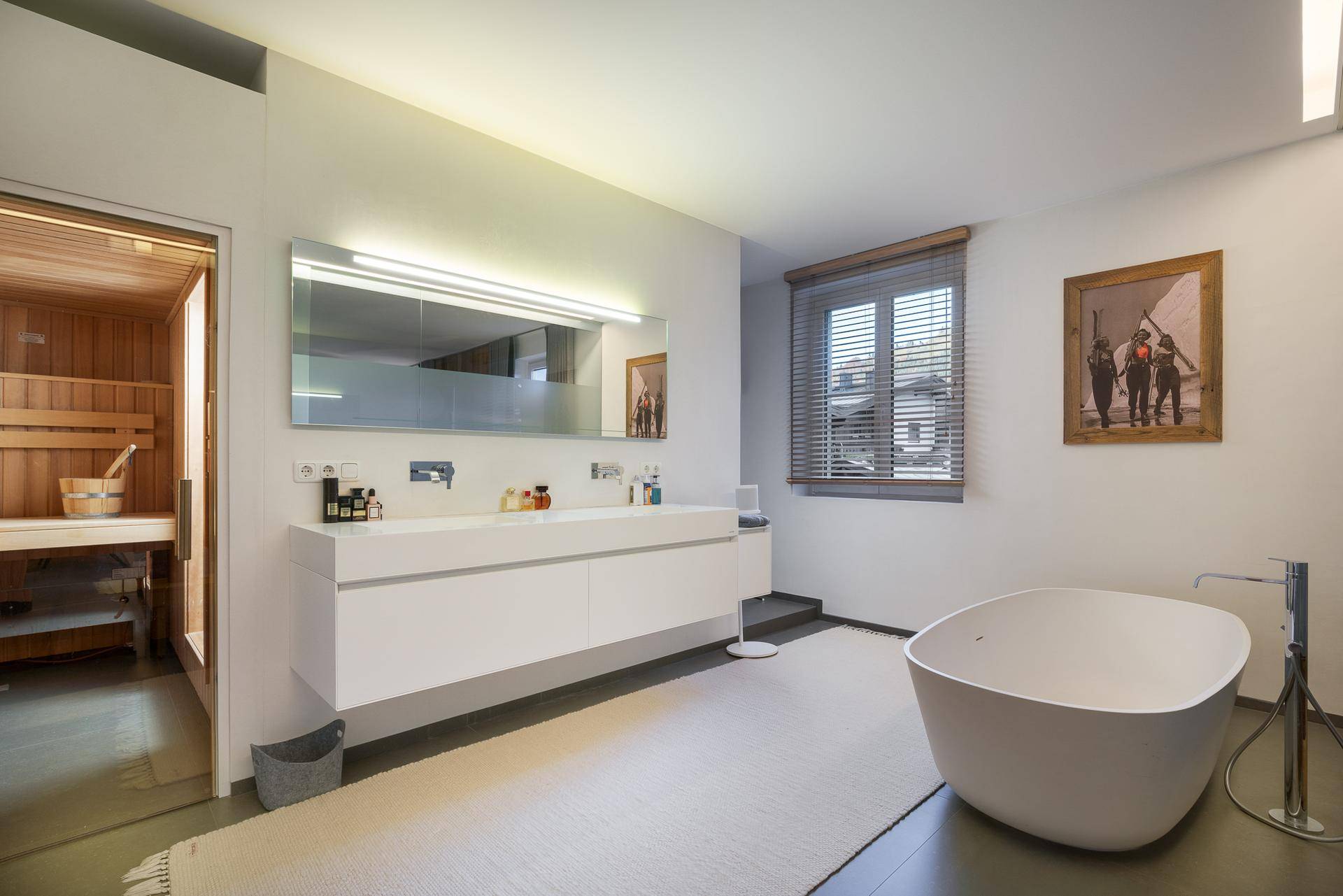 Luxuriöses Badezimmer mit freistehender Badewanne, Doppelwaschbecken und direktem Zugang zur Sauna.