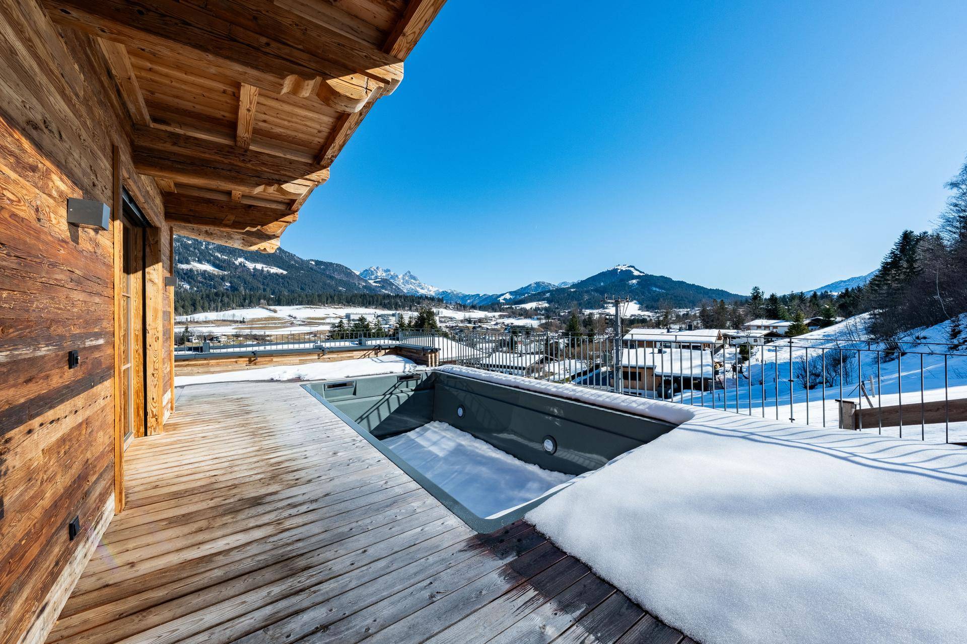Terrasse mit eingelassenem Whirlpool und atemberaubendem Panoramablick auf die verschneiten Berge.
