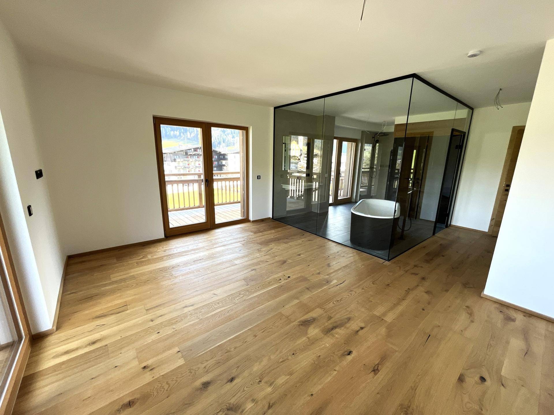 Geräumiges Schlafzimmer mit Holzboden und integriertem Badezimmerbereich mit freistehender Wanne.