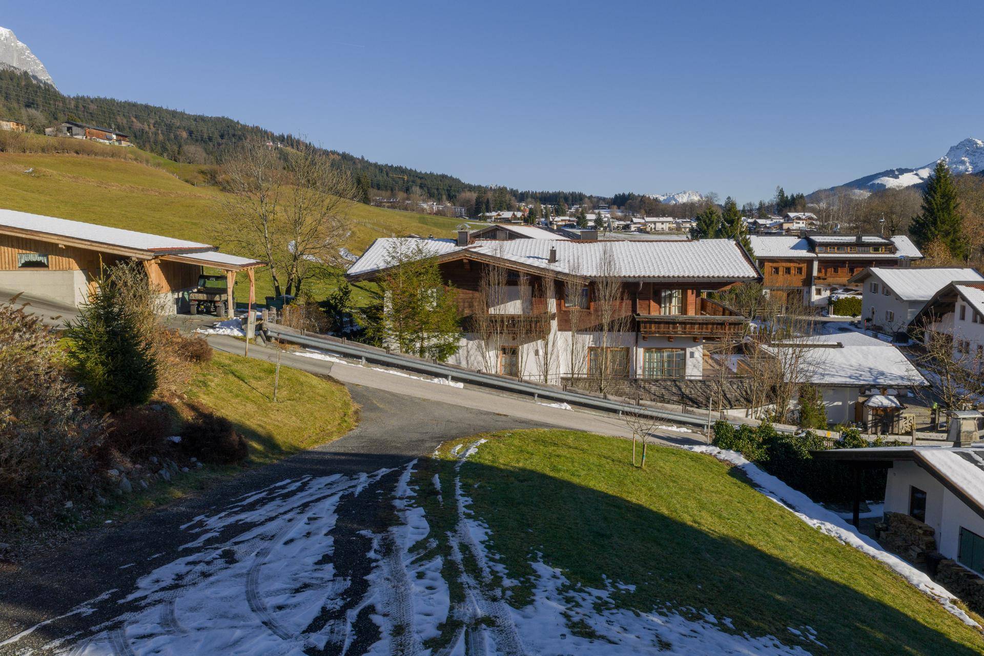 Panoramablick auf traditionelle Häuser mit schneebedeckten Dächern und majestätischen Bergen im Hintergrund.