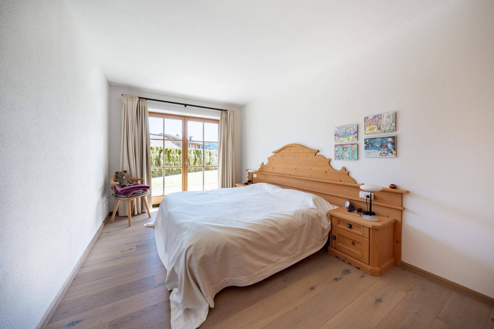 Helles Schlafzimmer mit Holzbett, Holzboden und direktem Zugang zum Garten.