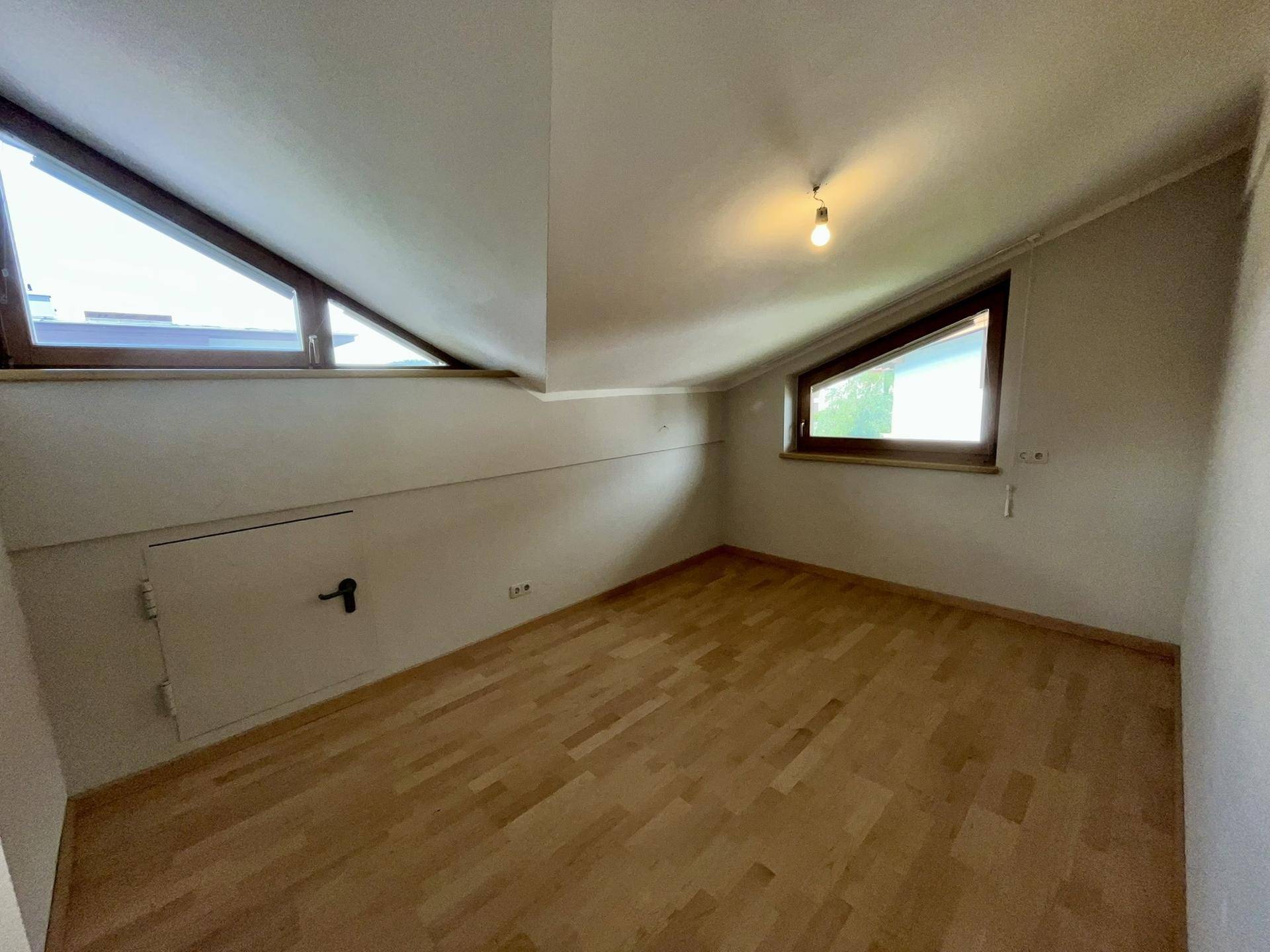 Heller Raum mit Holzboden und Dachschräge, ideal als kleines Schlafzimmer oder Arbeitszimmer.