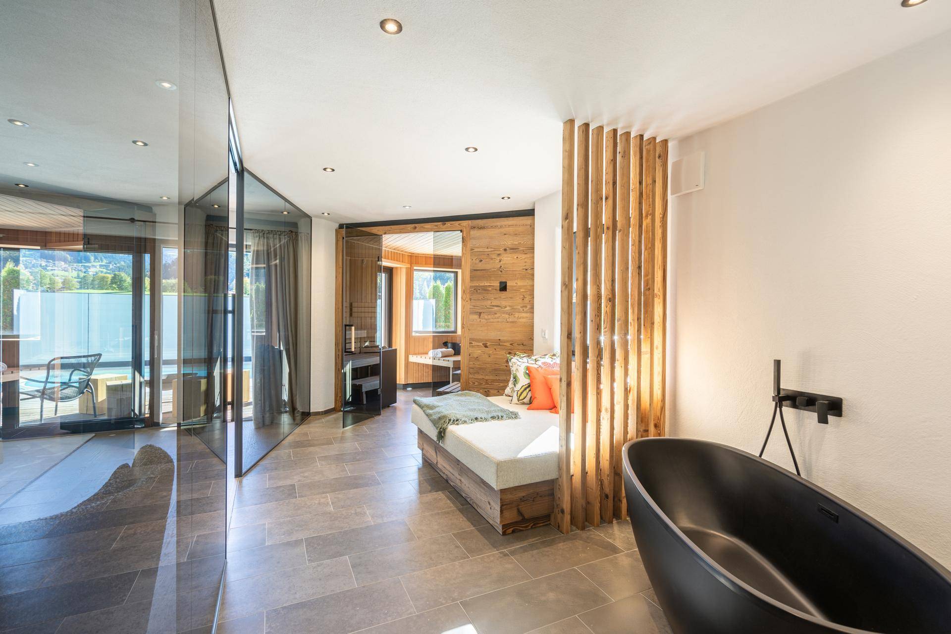 Elegantes Badezimmer mit freistehender Badewanne, Holzelementen und Zugang zu einem Außenbereich.
