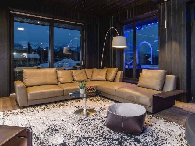 Gemütlicher Wohnbereich mit großem Ecksofa, Teppich und bodentiefen Fenstern mit Bergblick.