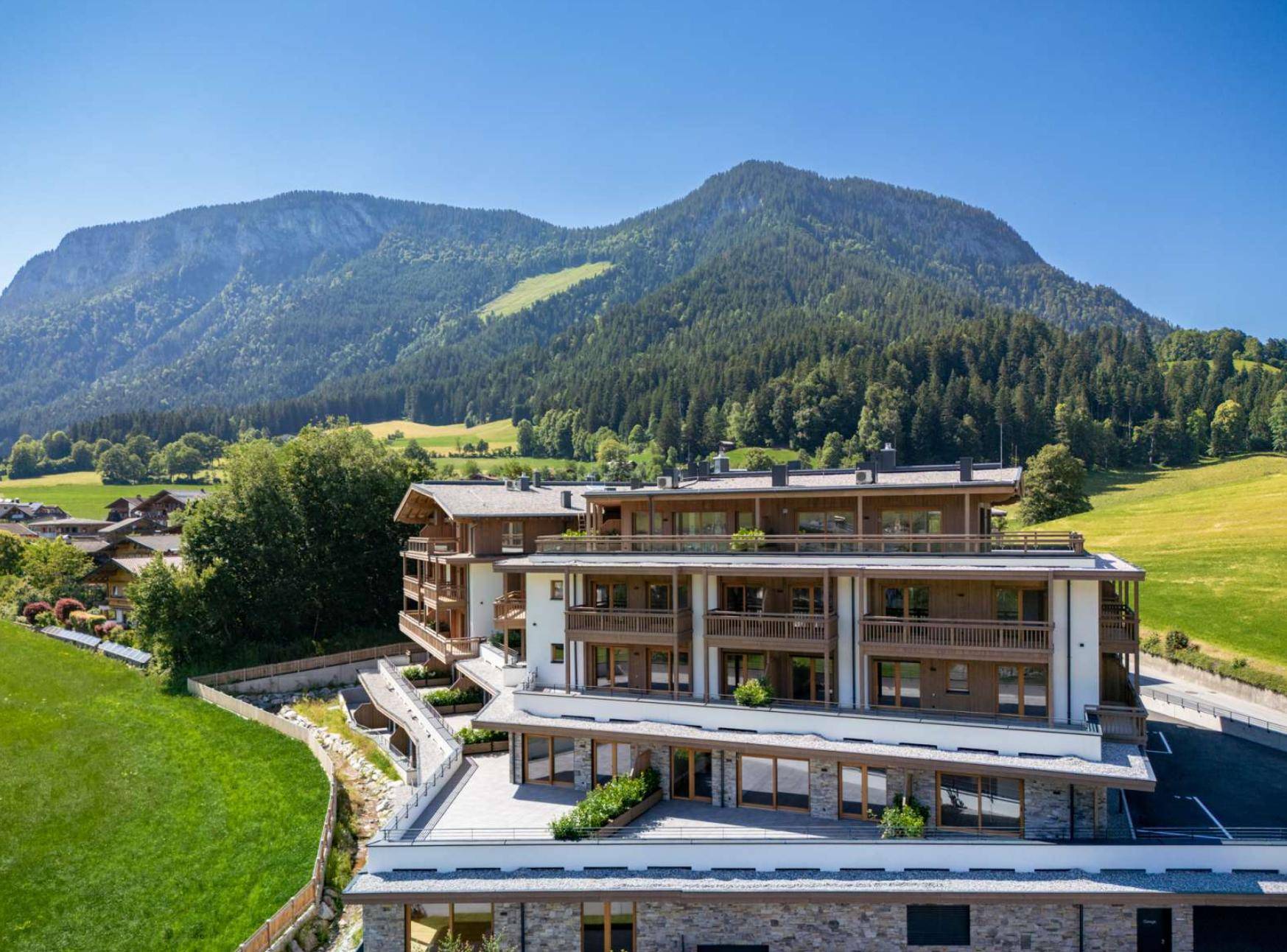 Großzügiges Wohngebäude in alpiner Landschaft mit Bergblick und viel Grünfläche.