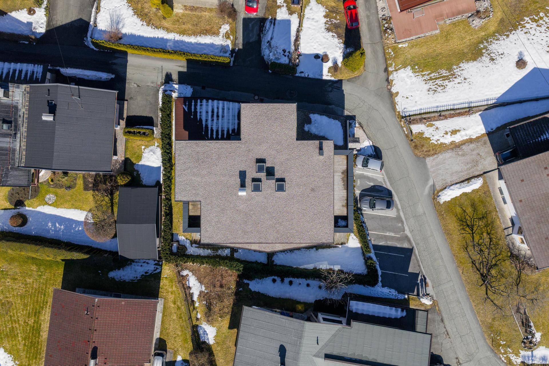 Luftaufnahme der Wohnanlage mit Flachdach und umliegenden Gärten in einer Siedlung.