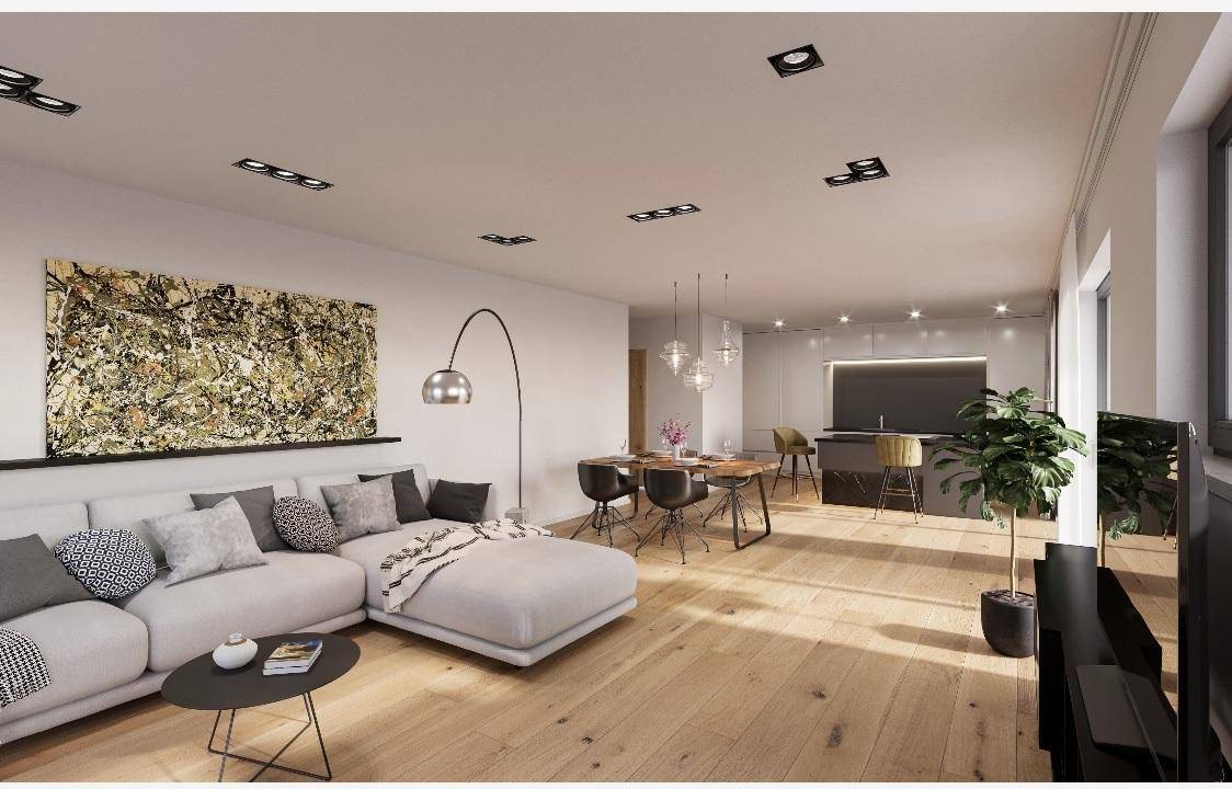 Geräumiger offener Wohnbereich mit Holzboden, bequemer Couch und integrierter moderner Küche.