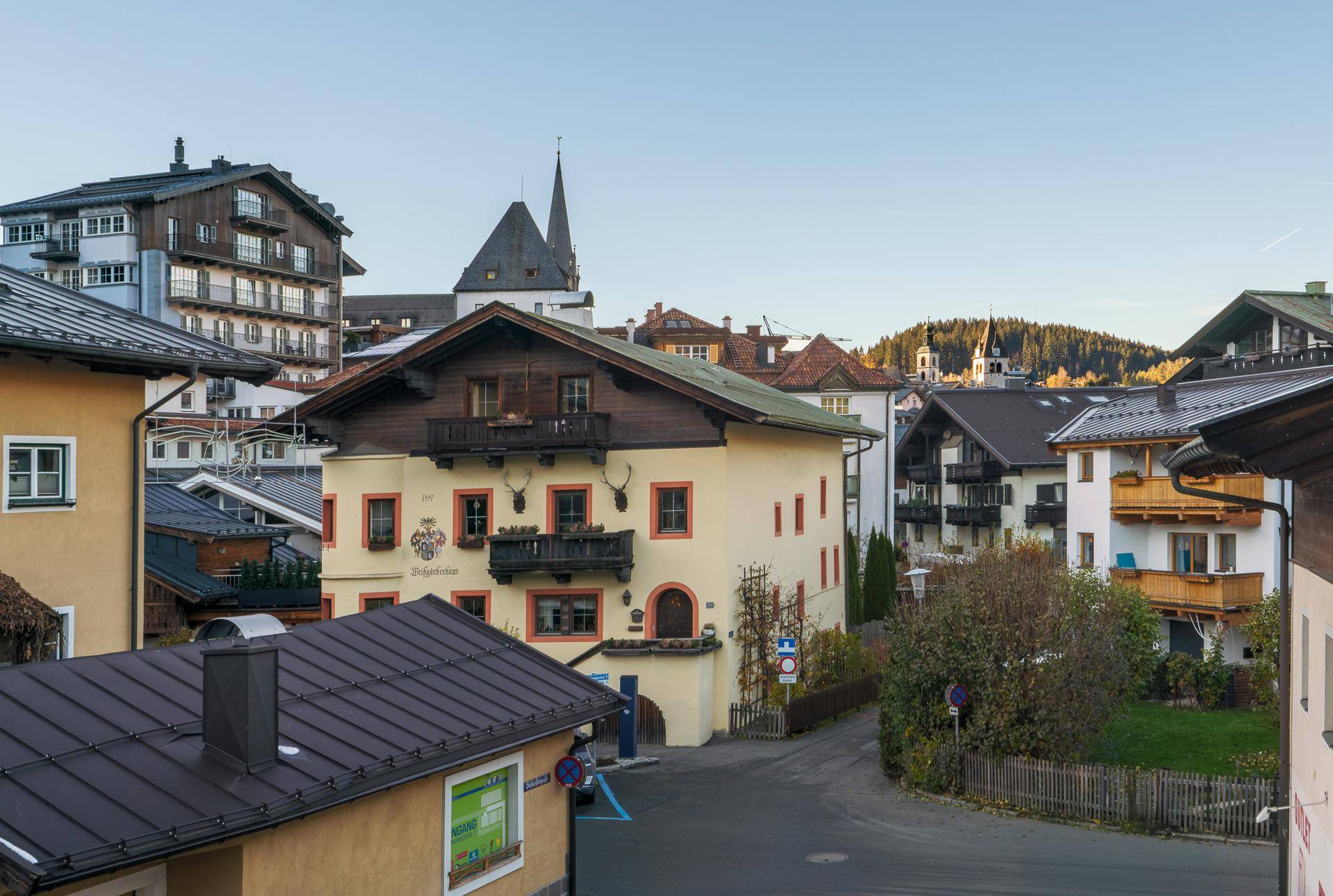 Panoramablick auf eine charmante Alpenstadt mit traditionellen Gebäuden und Kirchtürmen, umgeben von Bergen.