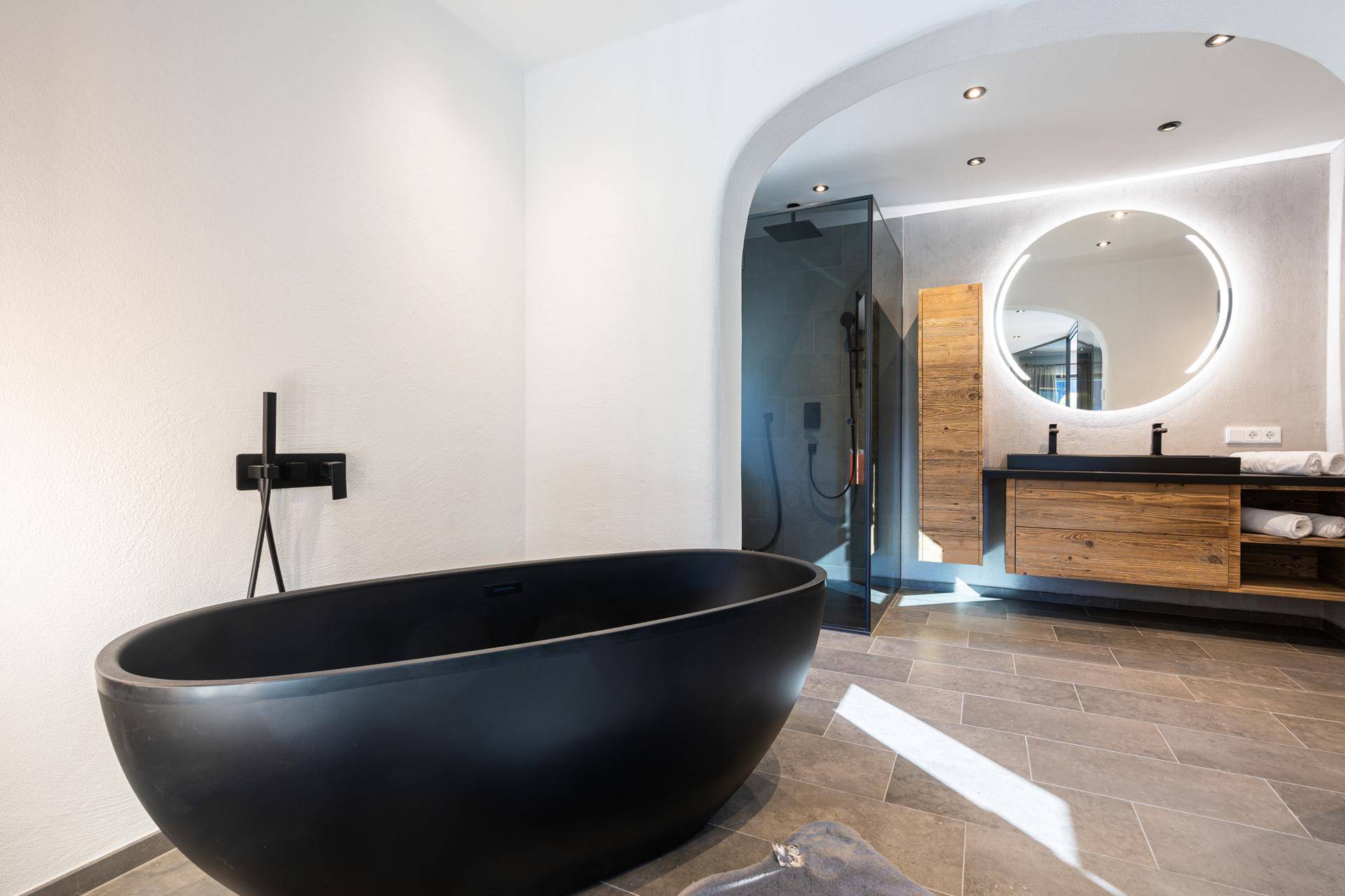 Modernes Badezimmer mit freistehender schwarzer Badewanne, begehbarer Dusche und Doppelwaschbecken.