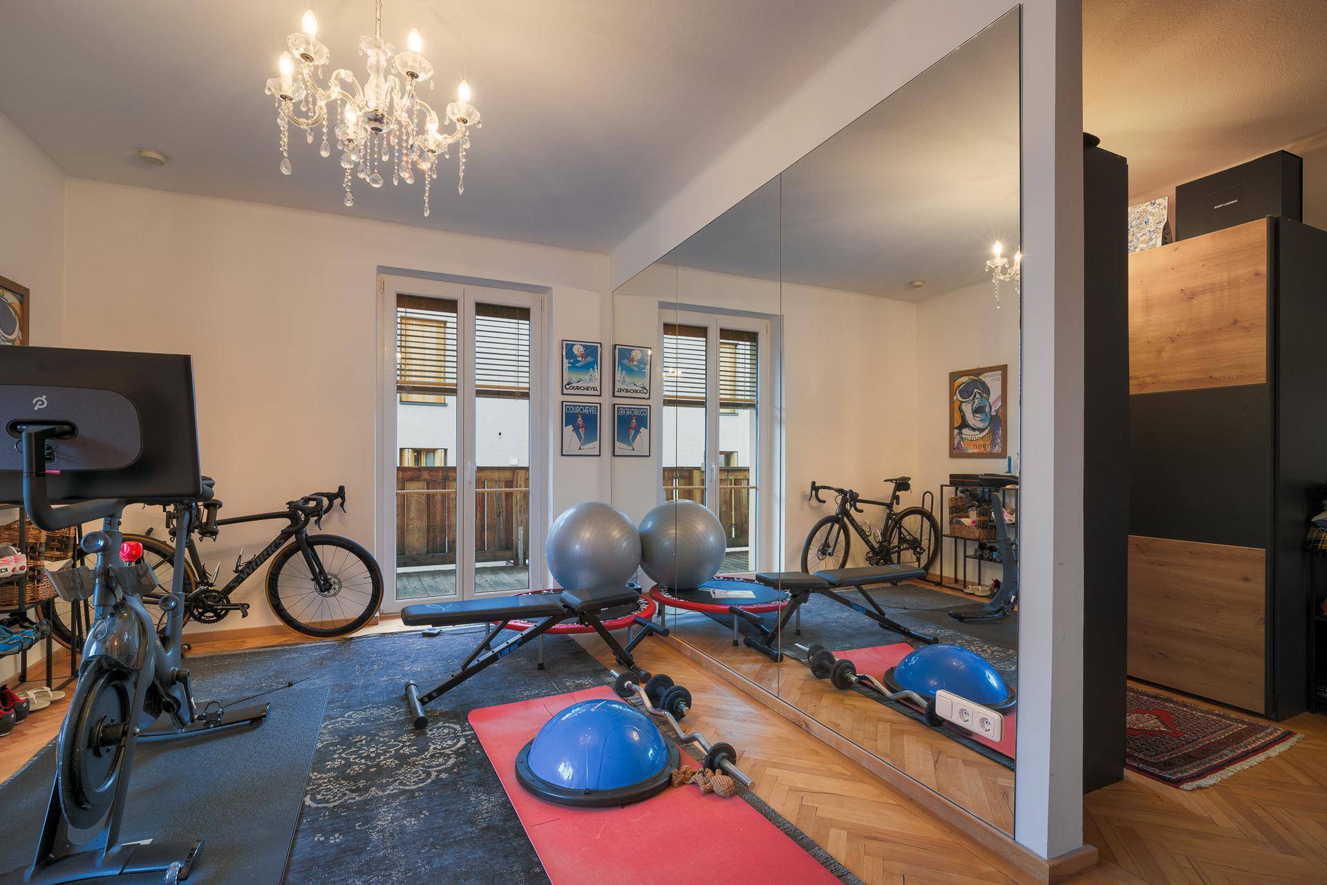 Fitnessraum mit Trainingsgeräten, Spiegelwand und Zugang zu einem französischen Balkon, hell und geräumig.