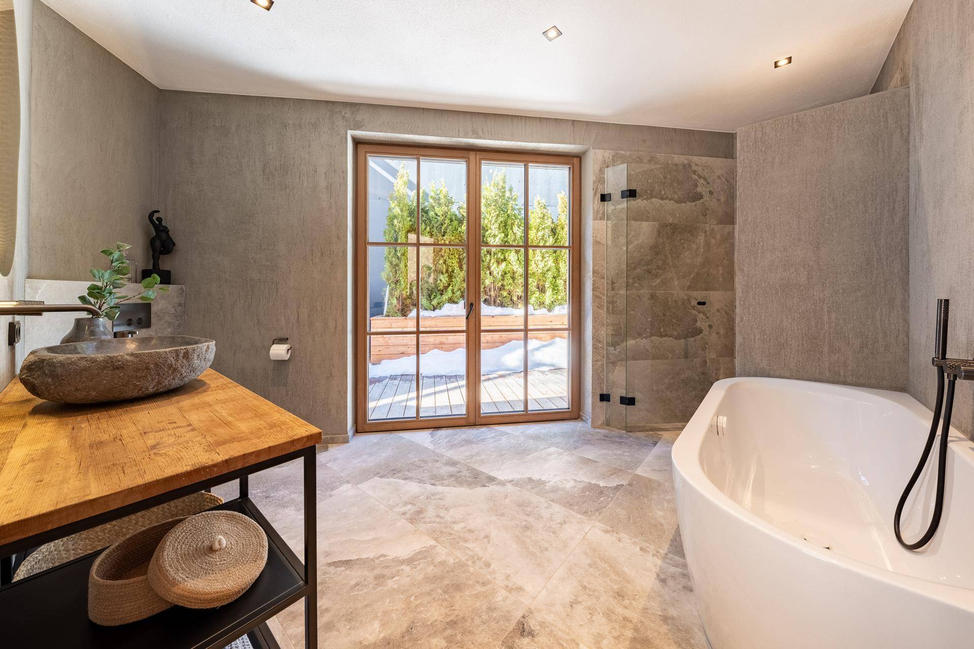 Elegantes Badezimmer mit freistehender Badewanne, Steinwaschbecken und großem Fenster.