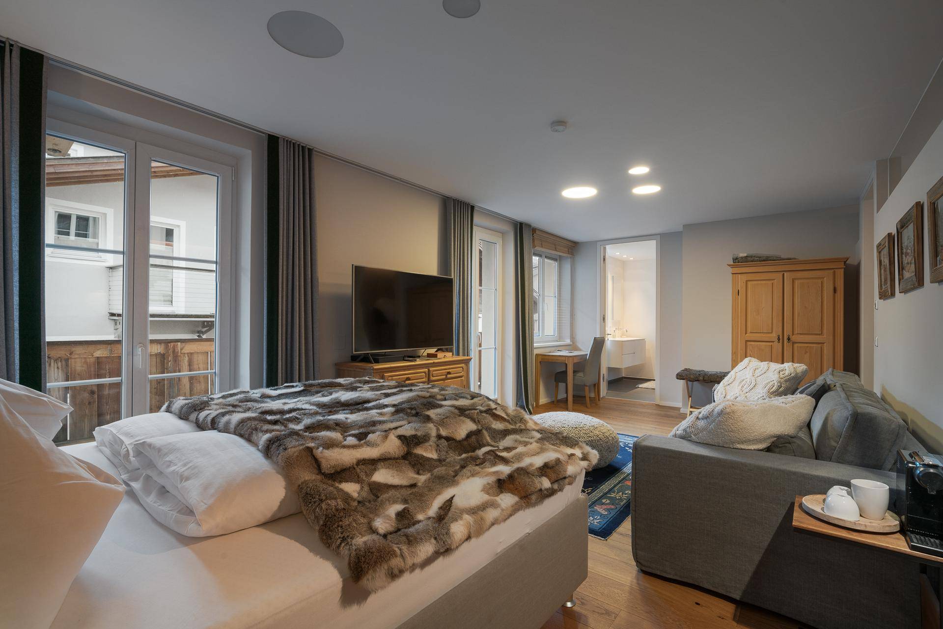 Helles Schlafzimmer mit großem Bett, Sofa und Holzboden, bietet direkten Zugang zum Außenbereich.