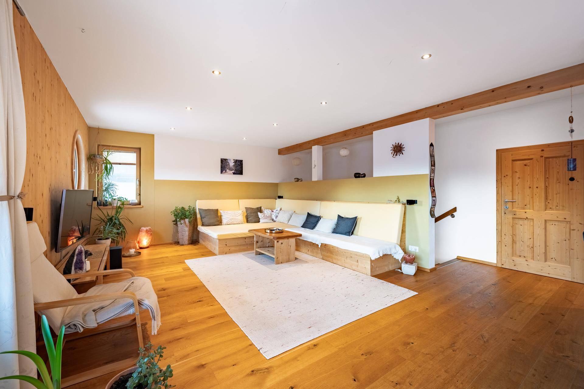 Gemütliches Wohnzimmer mit Holzboden, Holzwänden und bequemen Sitzgelegenheiten.