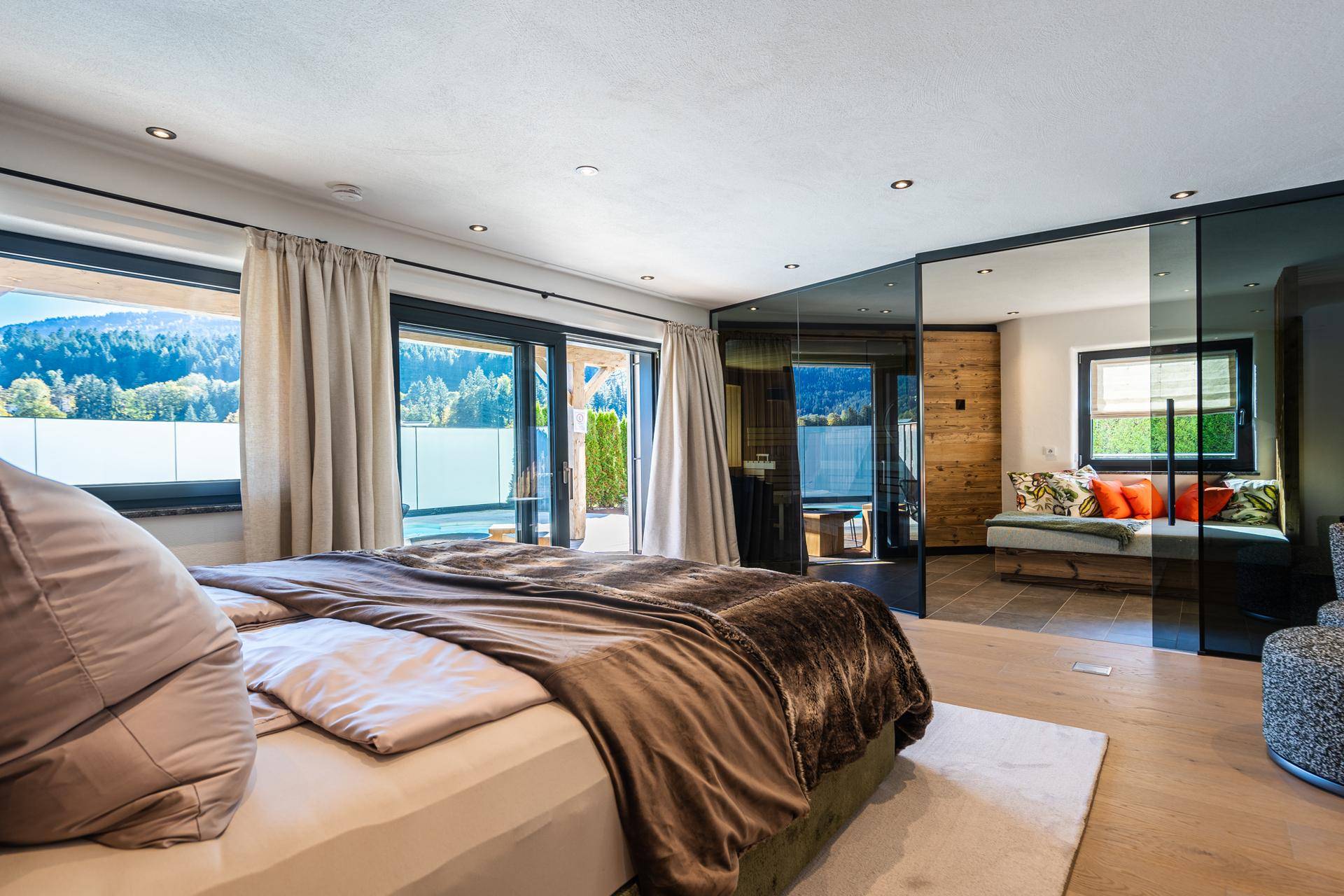 Helles Schlafzimmer mit Holzboden, großzügigen Fenstern und Zugang zu einem Außenbereich.