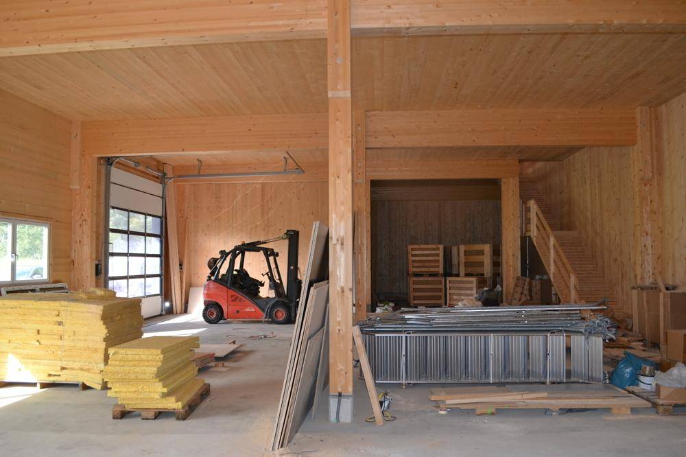 Geräumiger Lagerraum im Bau mit Holzbalken, einem großen Rolltor und einem Gabelstapler.
