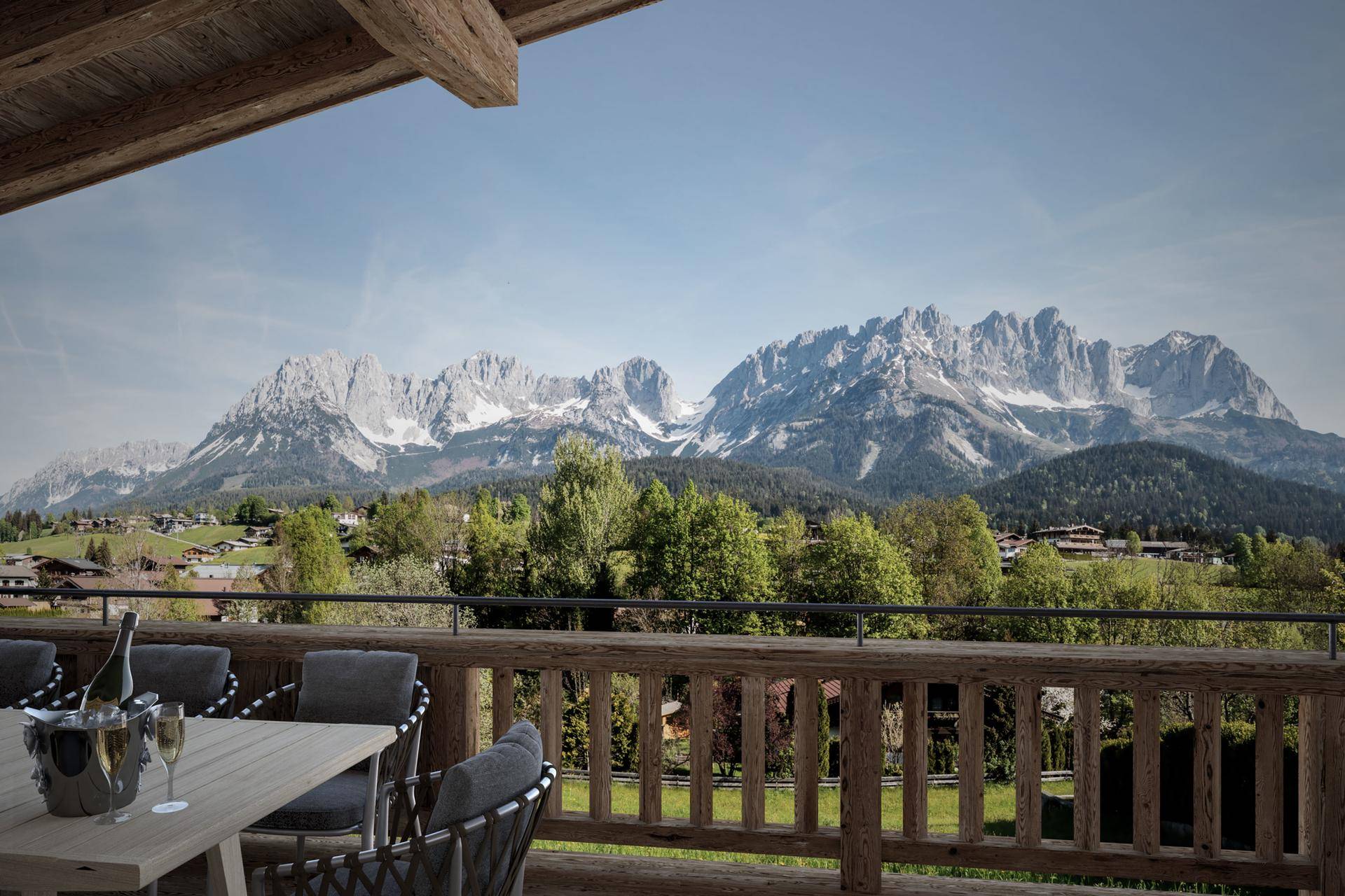 Geräumiger Balkon mit Esstisch und Champagner, bietet einen atemberaubenden Panoramablick auf die Berge.