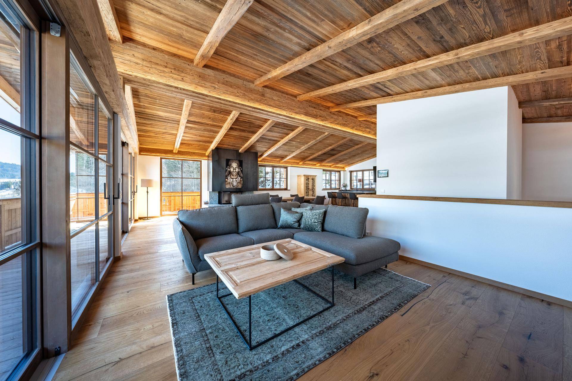 Gemütlicher Wohnbereich mit großem Sofa, Holzboden und beeindruckendem Bergblick durch Panoramafenster.
