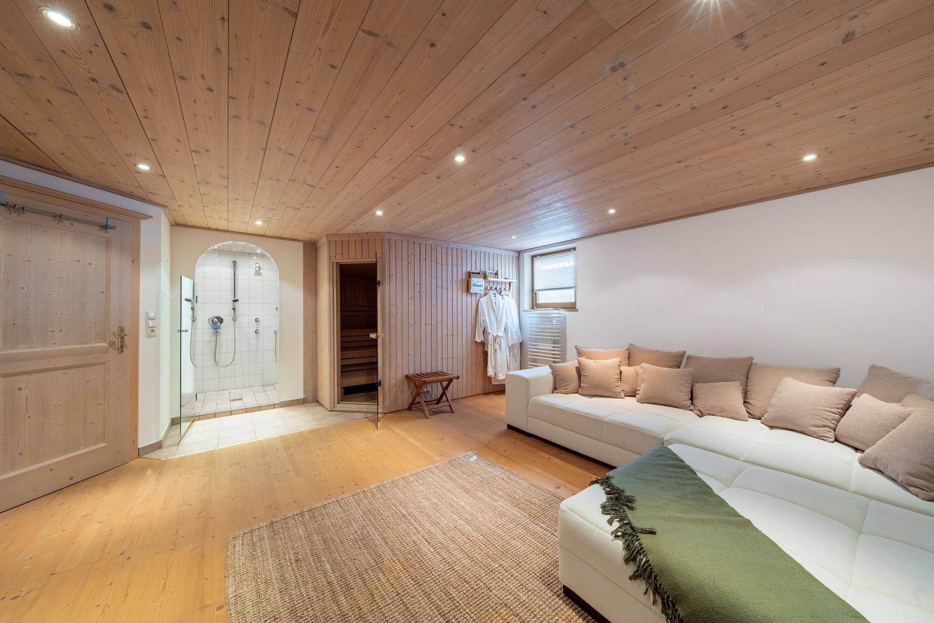 Entspannungsbereich mit Sauna, Dusche und einer bequemen Couch für Wellness-Momente und Erholung.