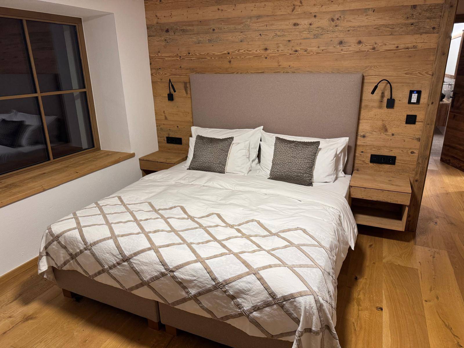 Helles Schlafzimmer mit Holzwänden, bequemen Bett und Nachttischen im rustikalen Stil.