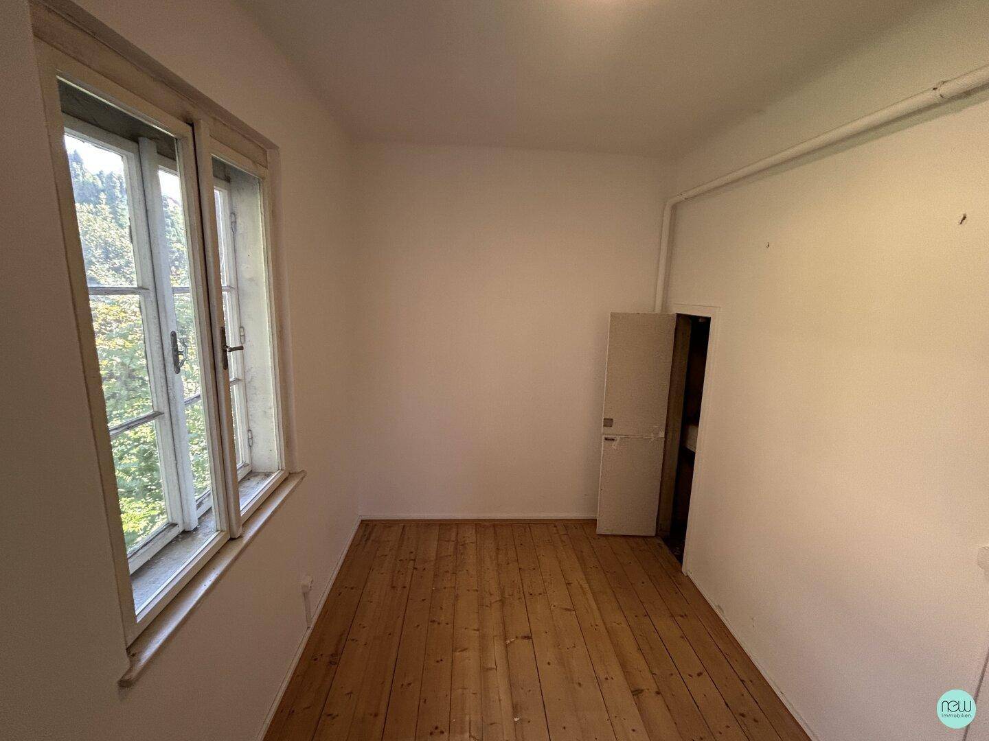 Kleineres, helles Zimmer mit Holzdielenboden und Fenster, das viel Tageslicht hereinlässt.