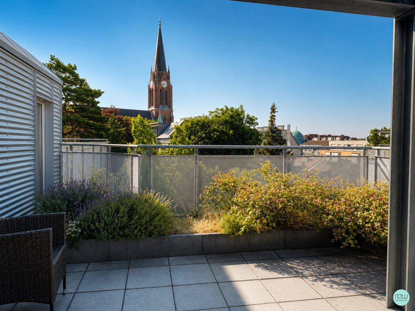 Dachterrasse mit Fliesenboden, Pflanzen und einem malerischen Blick auf eine Kirche.