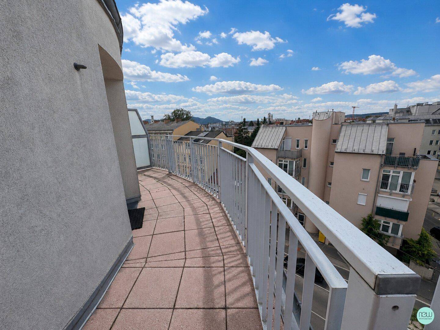 Langer, geschwungener Balkon mit Fliesenboden und weitem Blick über die Stadt und die umliegenden Hügel.