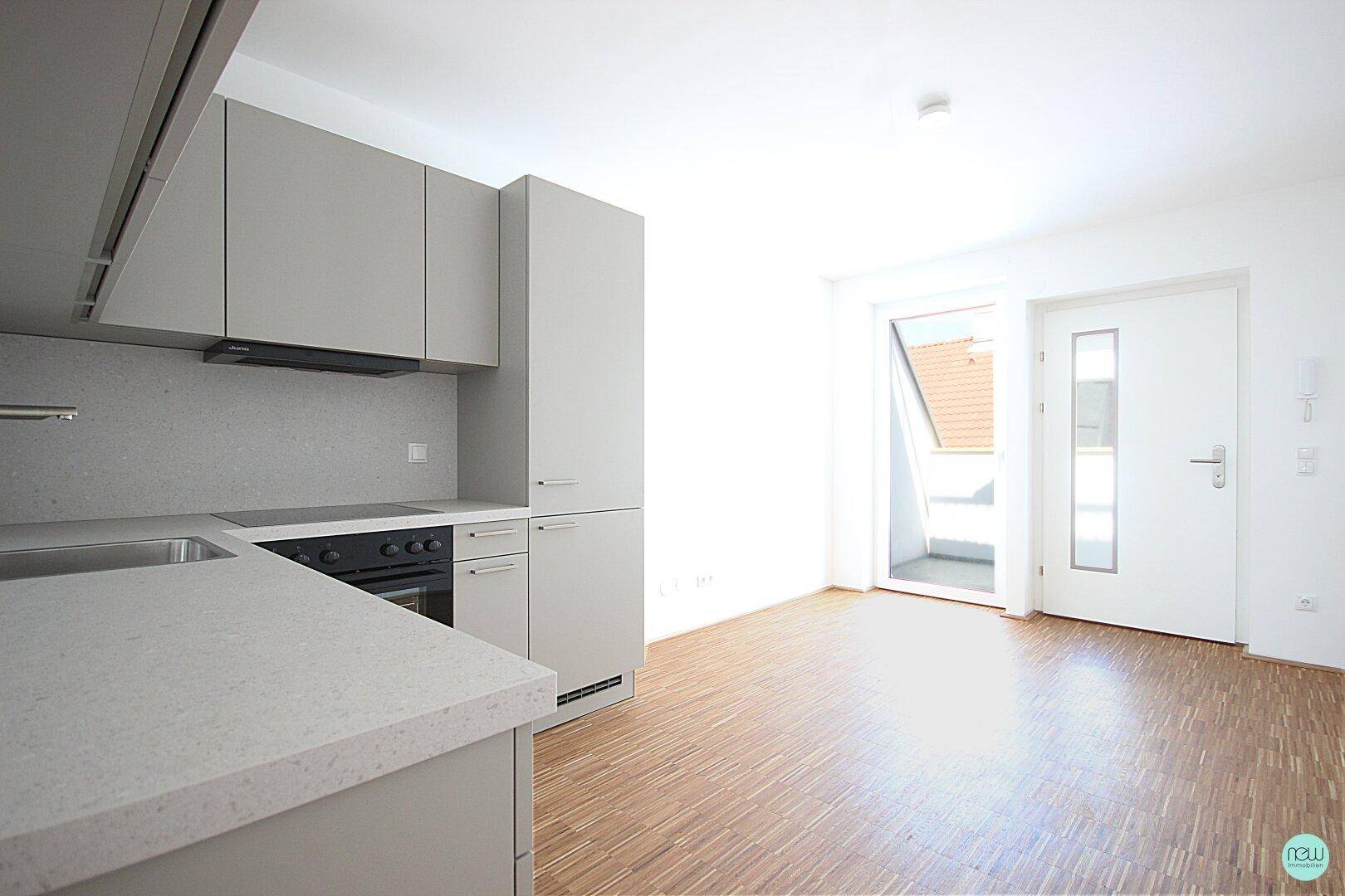 Moderne Einbauküche in Grau mit integrierten Geräten und Zugang zu einem Balkon.