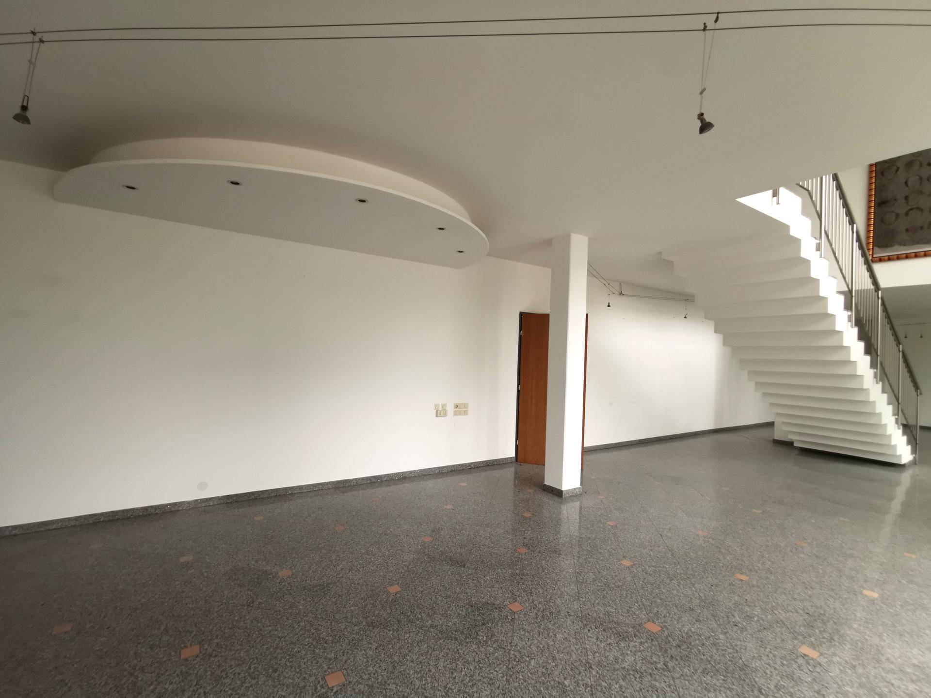 Heller Empfangsbereich mit eleganter Treppe, Terrazzoboden und moderner Deckengestaltung.