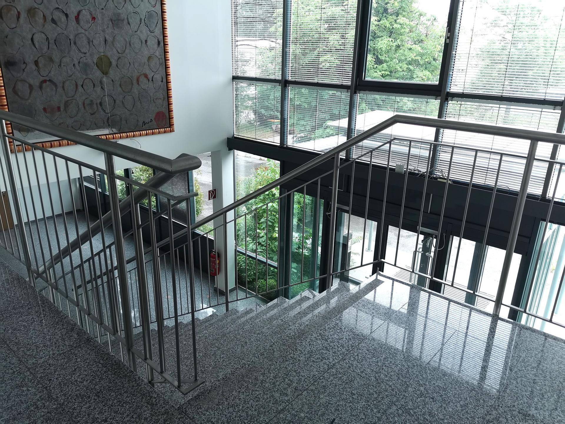 Blick von der oberen Etage auf den Eingangsbereich mit Treppe und großen Fensterfronten.