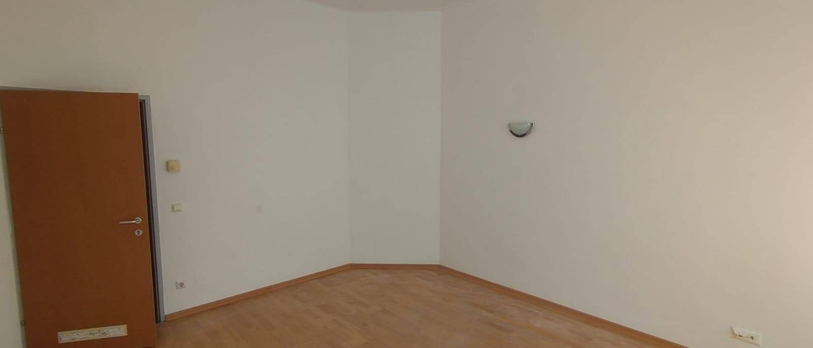 Leerer Raum mit Holzboden und einer Tür, ideal für ein Schlaf- oder Wohnzimmer.
