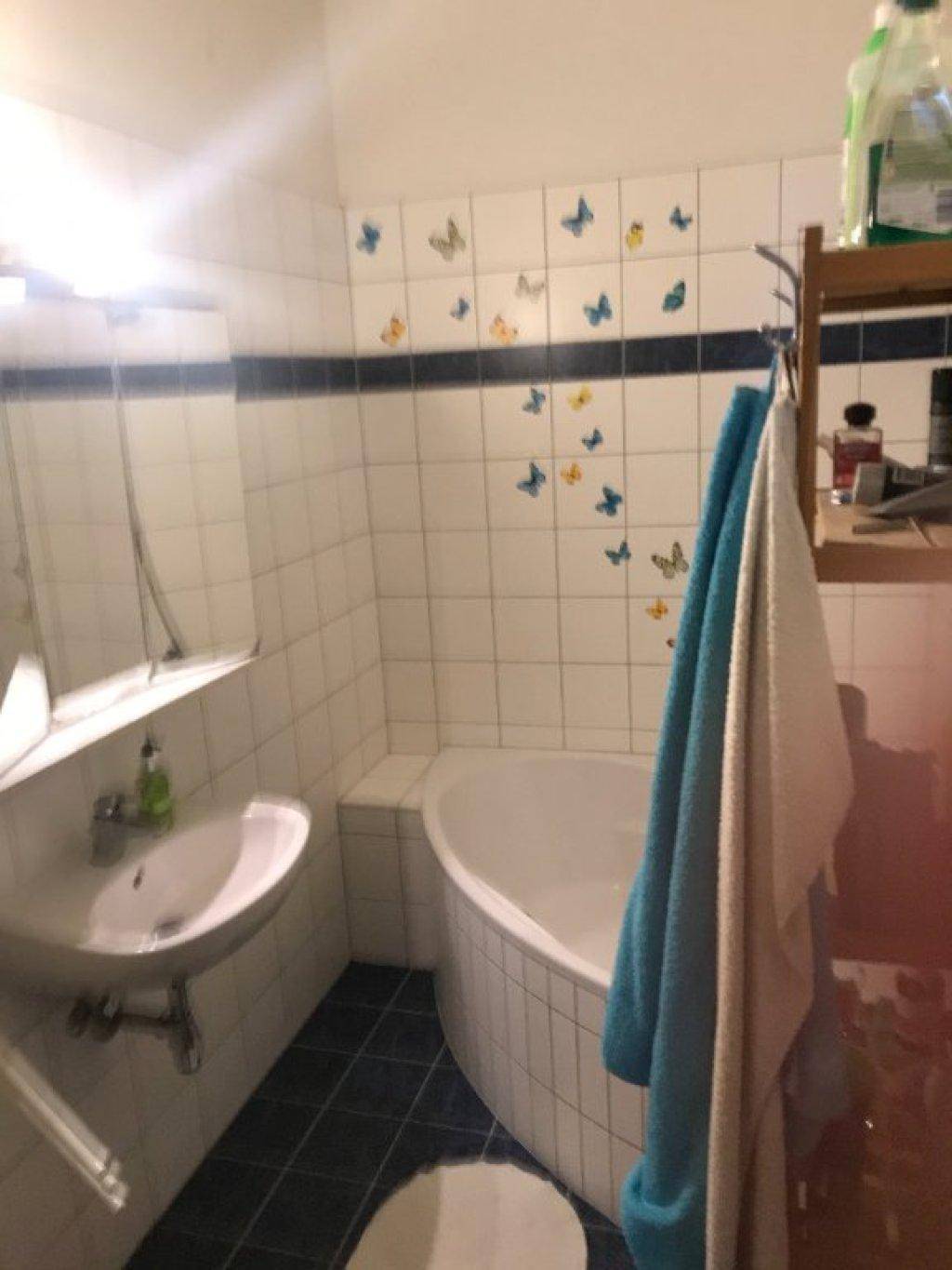 Badezimmer mit Eckbadewanne, Waschbecken und Handtüchern, dekoriert mit Schmetterlingsaufklebern.