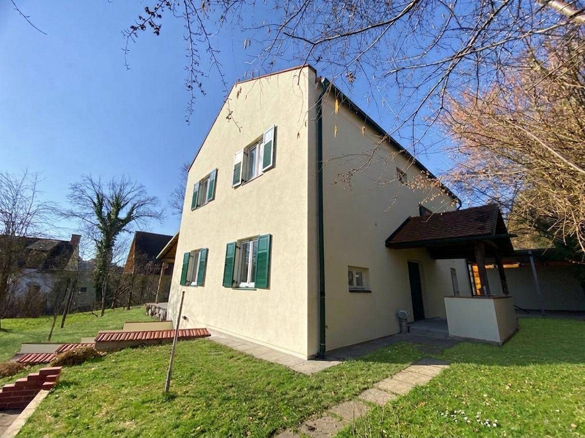 Seitenansicht des Hauses mit Eingangsbereich, umgeben von einem grünen Garten.