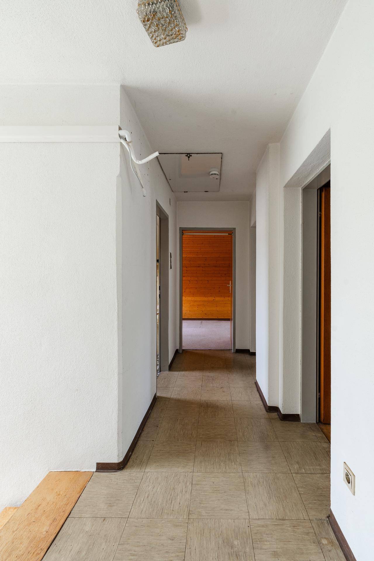 Langer Flur mit Fliesenboden und Zugang zu mehreren Zimmern.