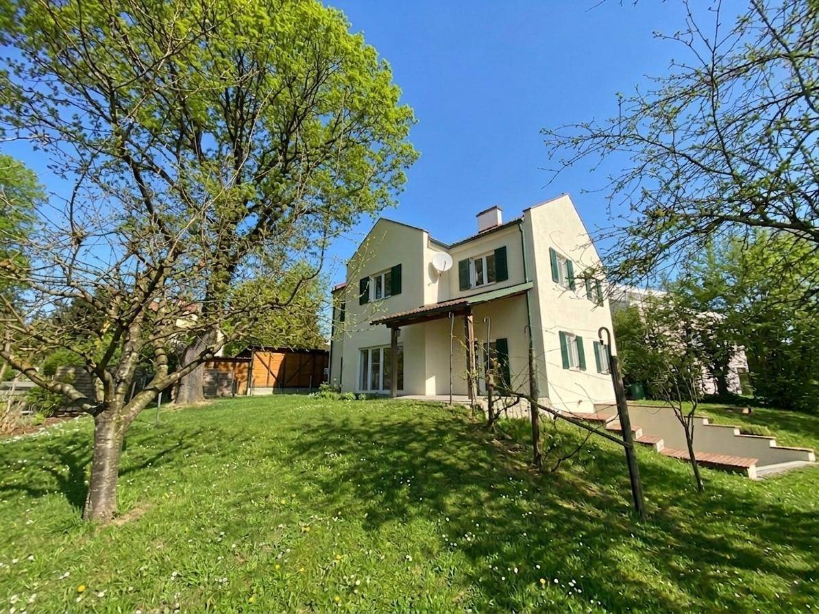 Seitenansicht des Hauses mit großem, leicht geneigtem Gartenbereich und viel Grün.