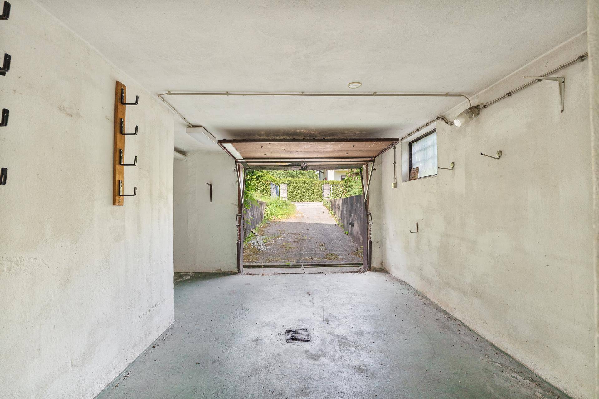 Einfache Garage mit offenem Tor und Blick auf die Einfahrt.