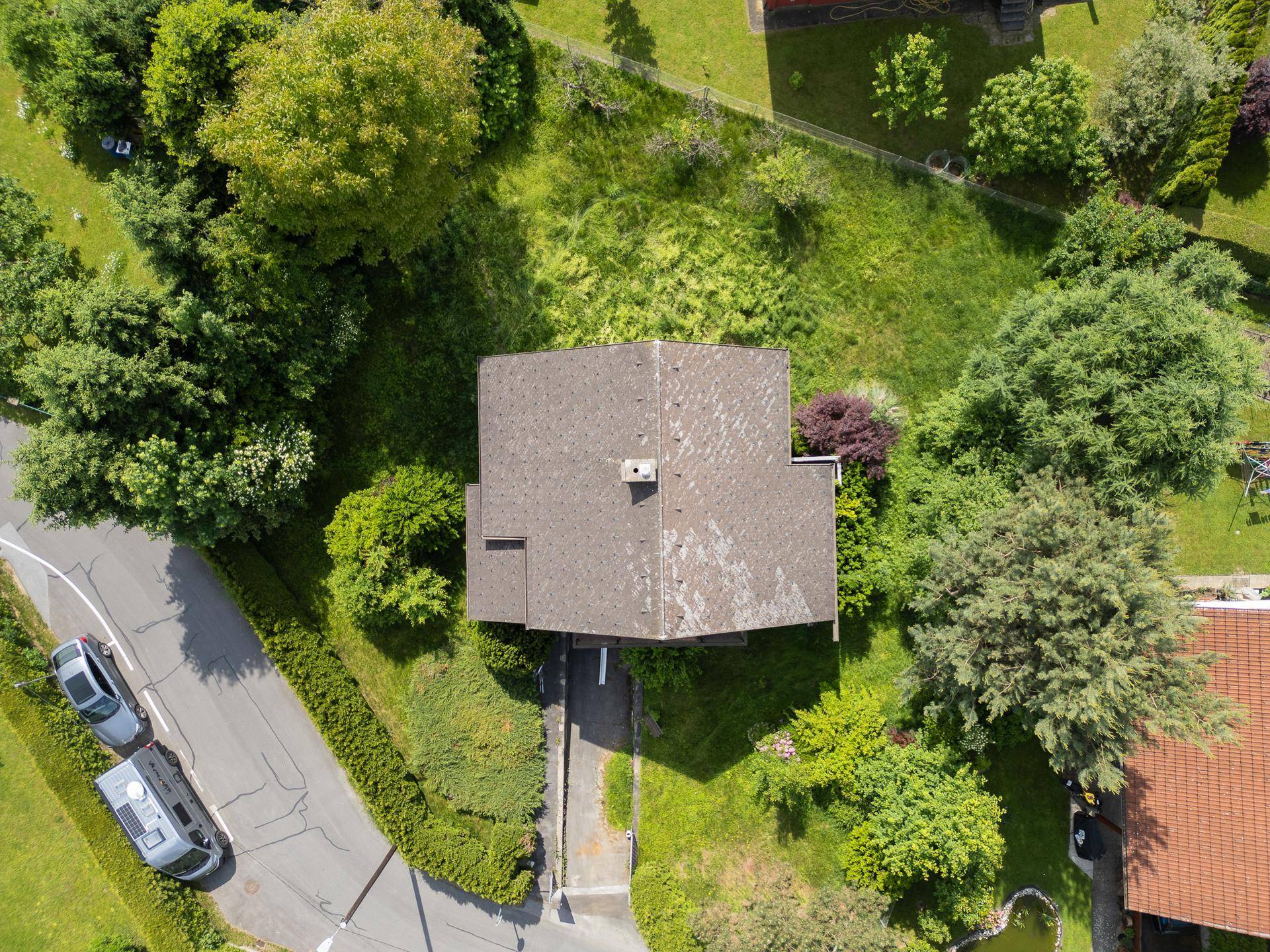 Luftaufnahme des Hauses mit Satteldach, umgeben von Bäumen und einer grünen Nachbarschaft.