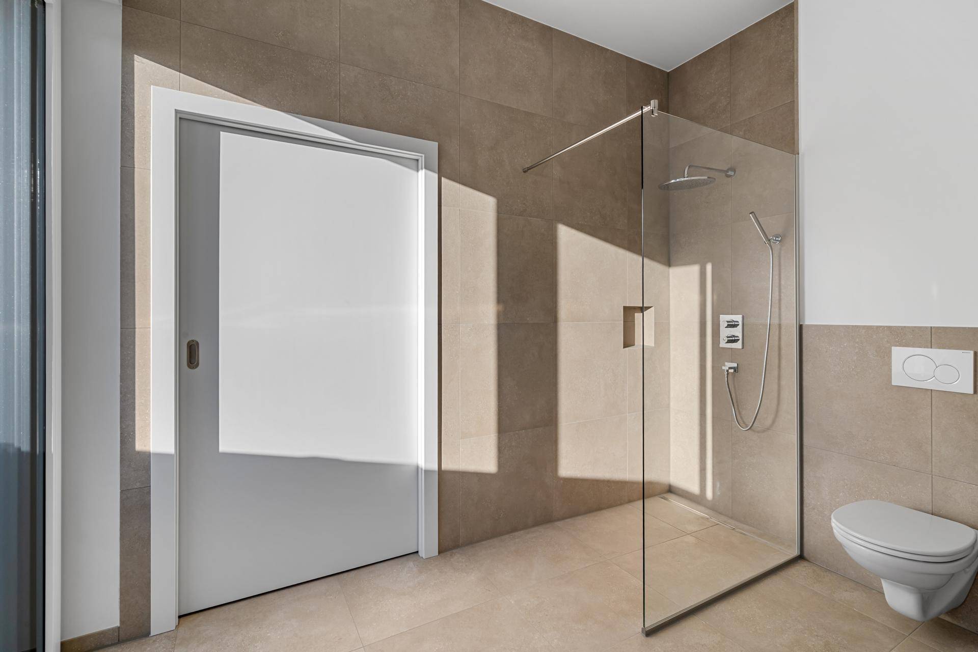 Modernes Badezimmer mit Schiebetür, begehbarer Dusche und Wand-WC in hellem Design.