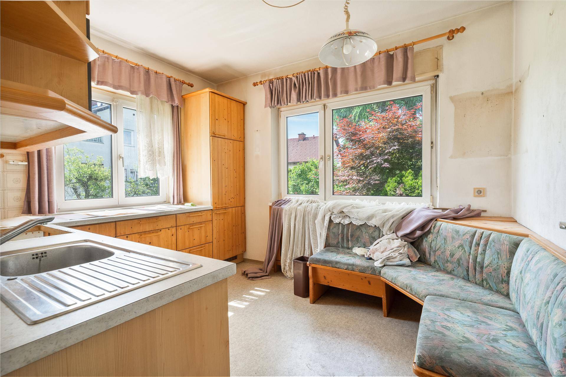 Helle Küche mit Holzmöbeln, Essbereich und Fenster mit Blick auf den Garten.