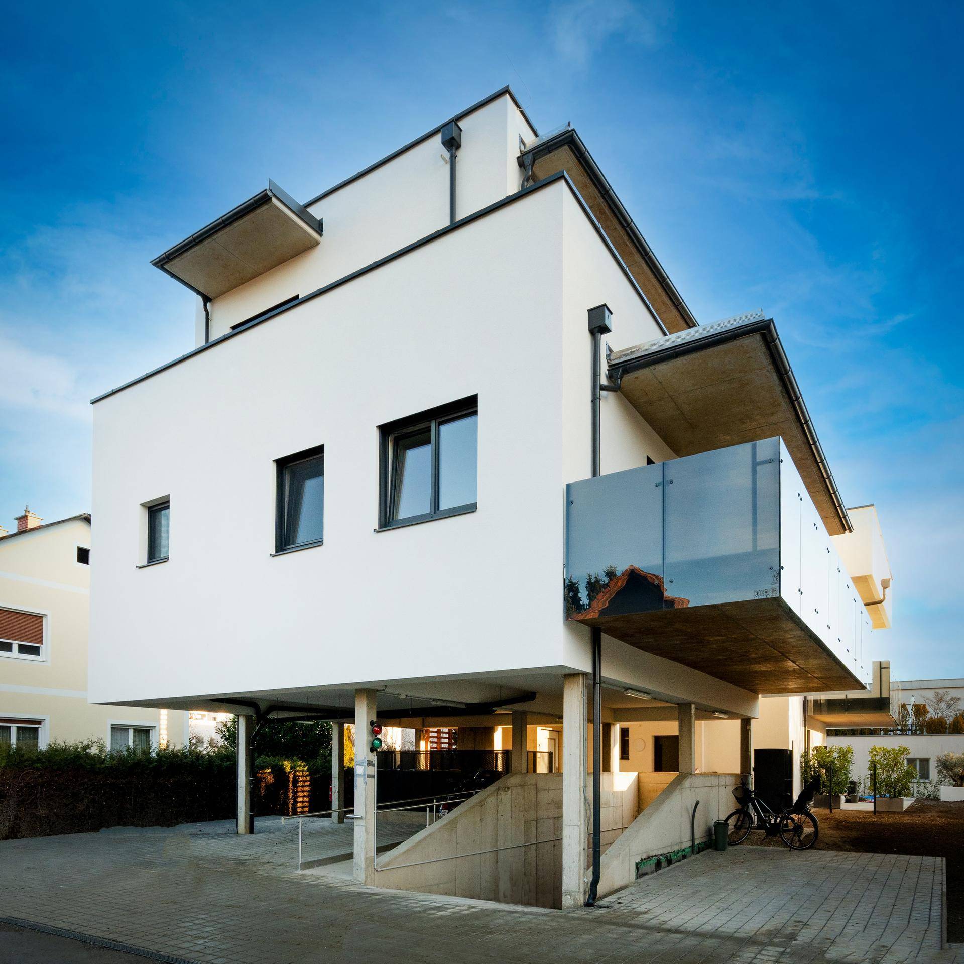 Modernes Gebäude mit klarer Architektur, Balkonen und Zugang zur Tiefgarage.