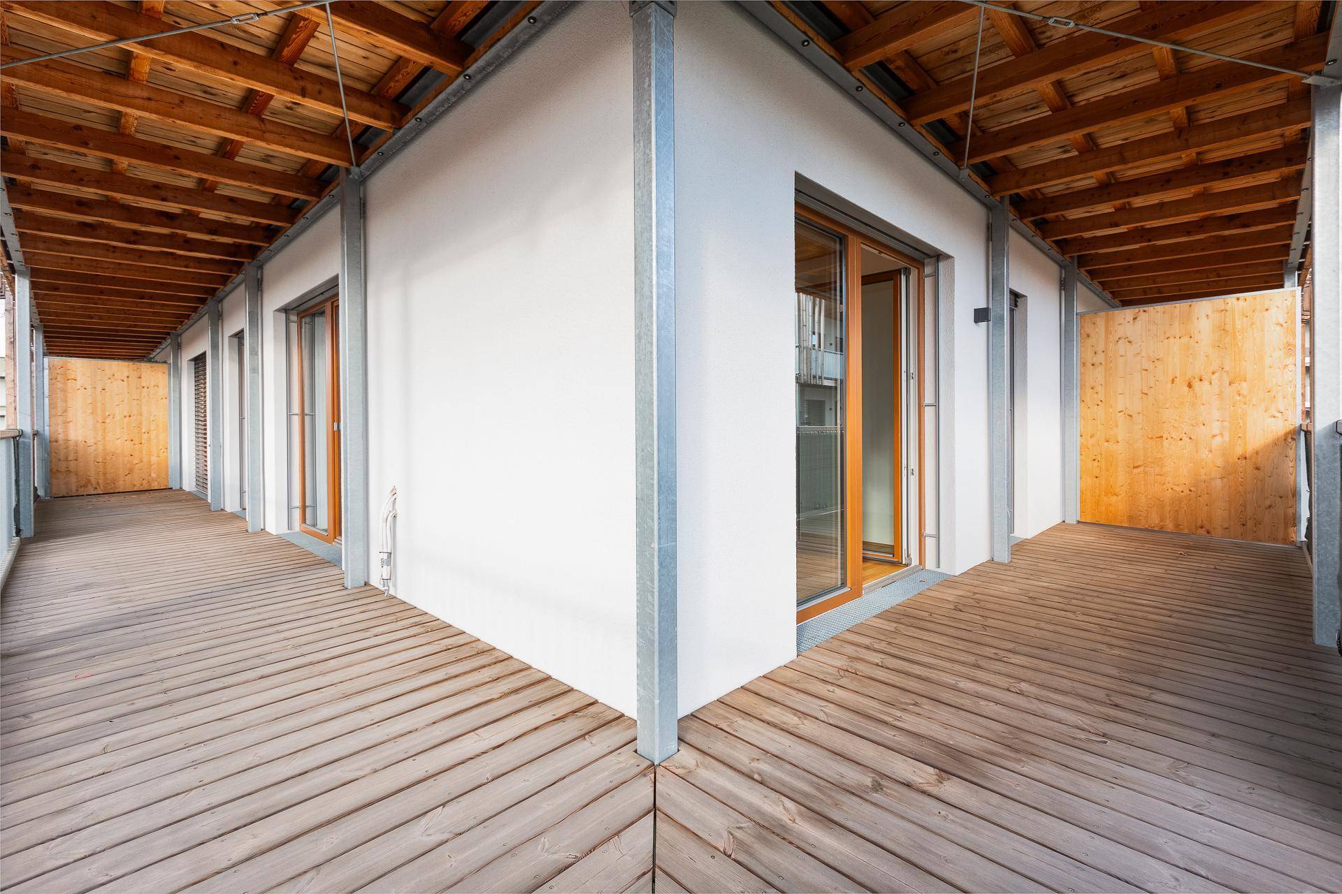 Eckbalkon mit Holzboden und Holzdecke, der einen geschützten Außenbereich bietet.