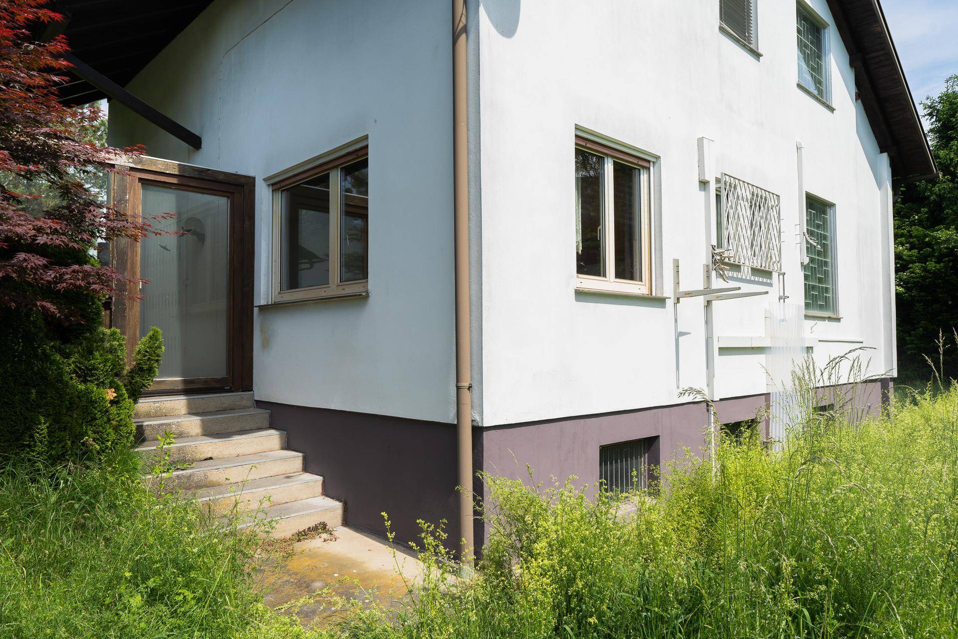 Seitlicher Eingangsbereich des Hauses mit Treppe und Zugang zum Untergeschoss.