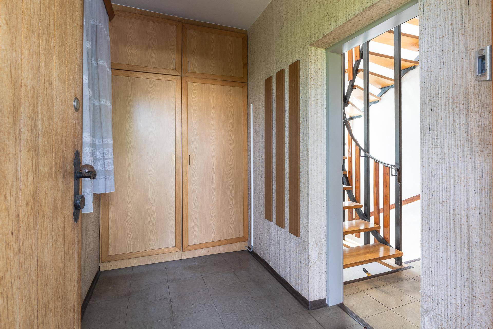 Eingangsbereich mit Einbauschränken und einer eleganten Holz-Wendeltreppe zum Obergeschoss.