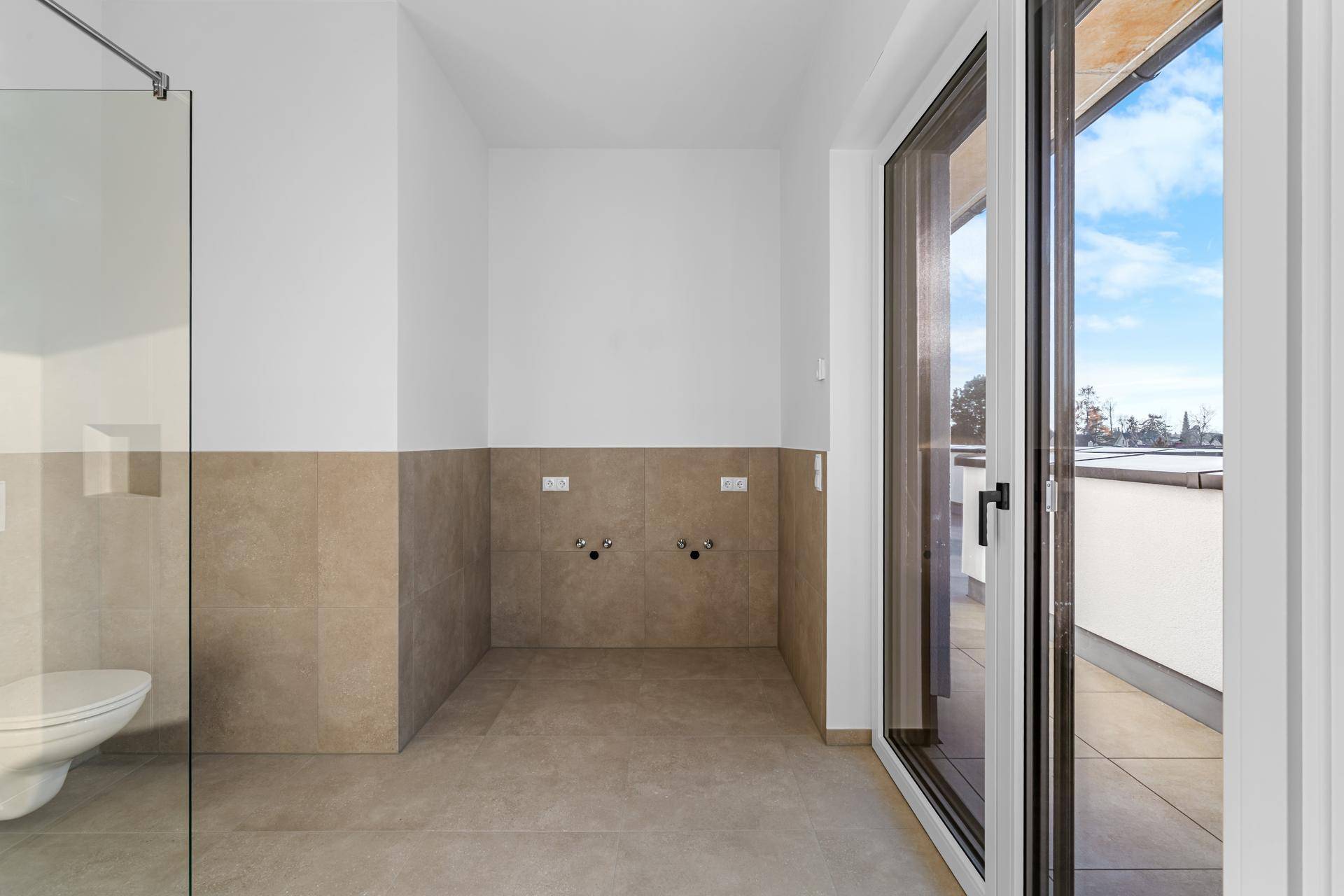 Modernes Badezimmer mit Duschbereich, Wand-WC und vorbereiteten Anschlüssen für Waschtisch.