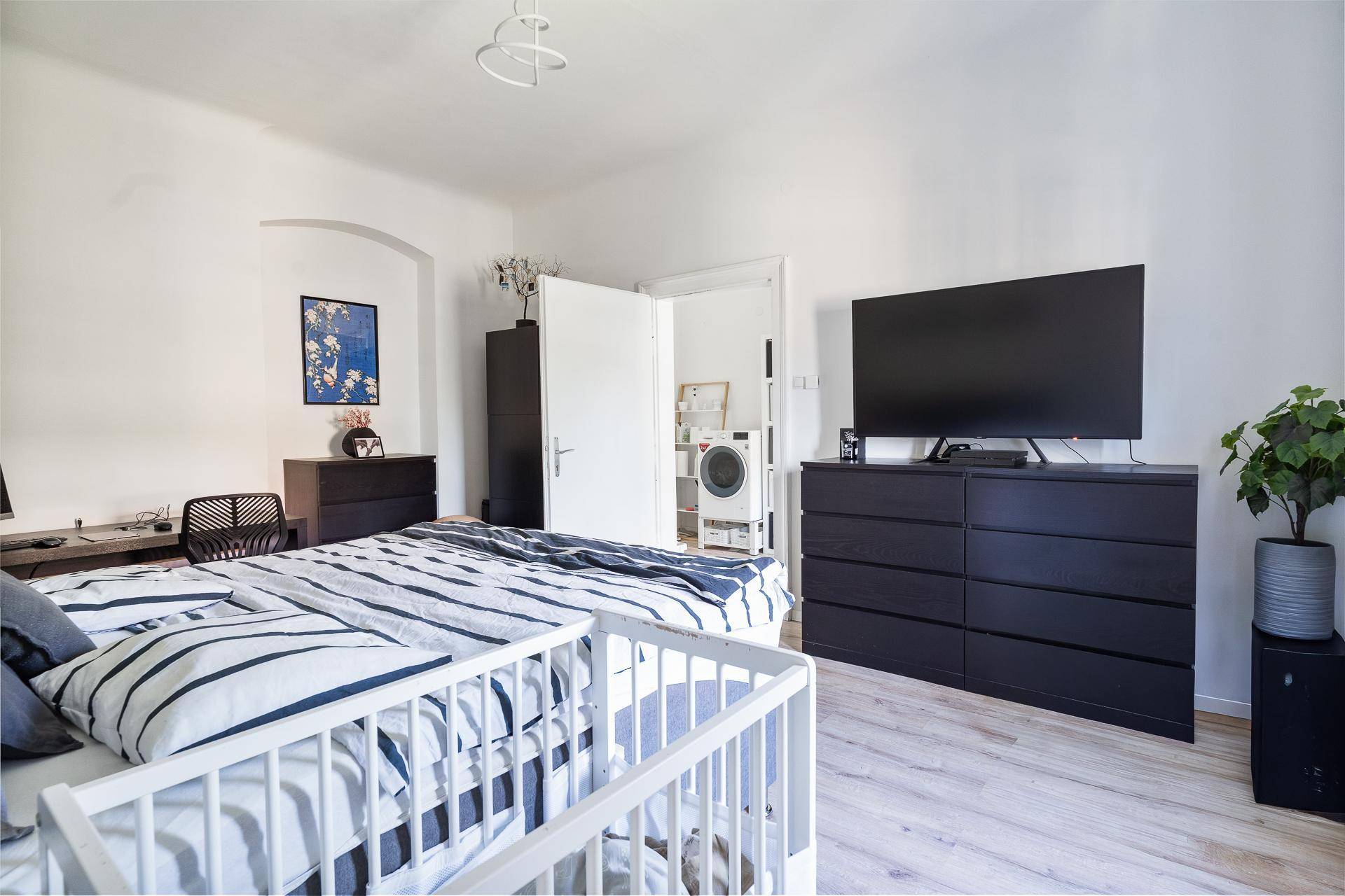 Geräumiges Schlafzimmer mit großem Bett, Fernseher und einem Babybett.