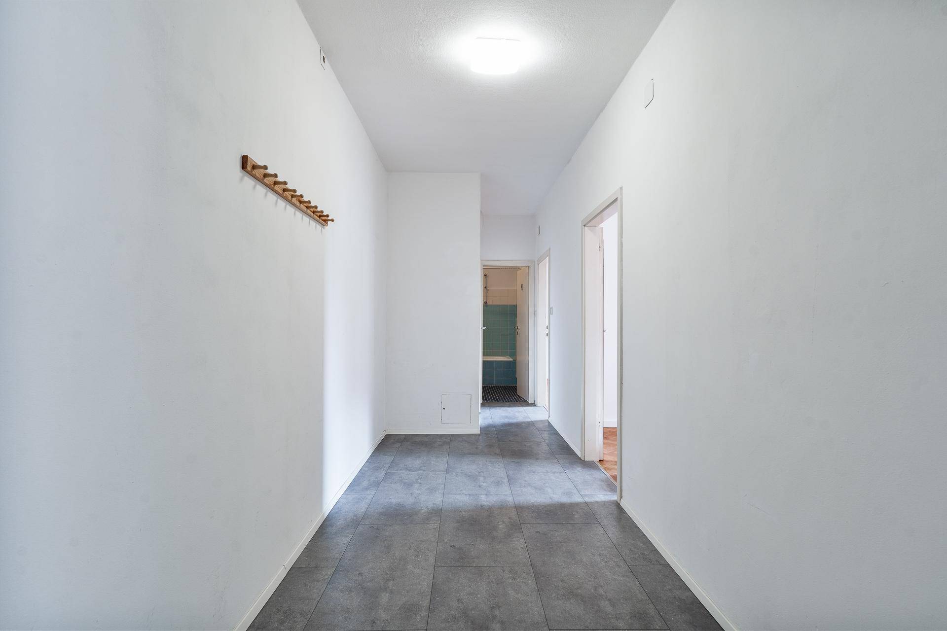 Heller Flur mit Fliesenboden und Garderobe, führt zu weiteren Räumen.