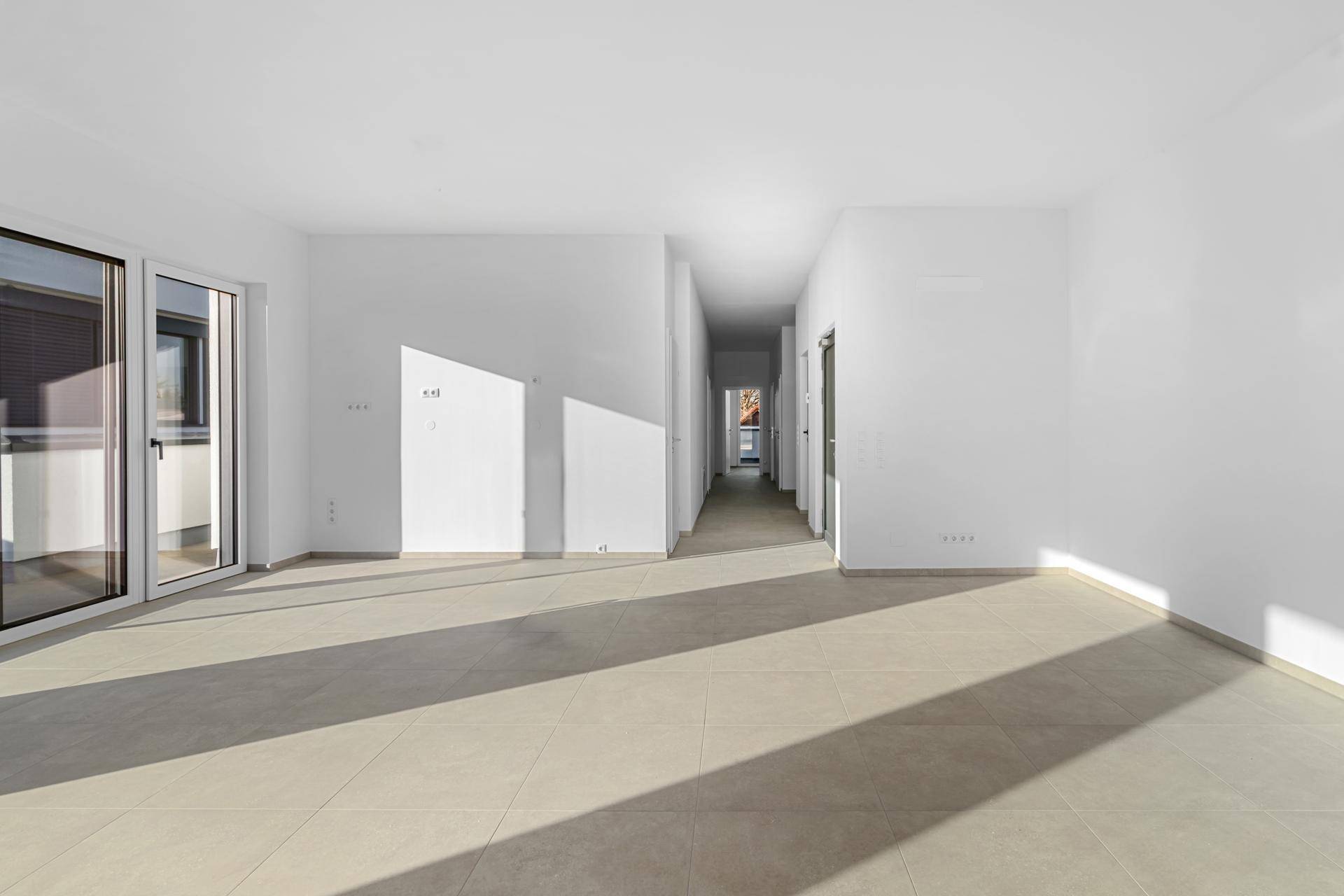 Langer, heller Flur mit Fliesenboden, der zu verschiedenen Räumen der Wohnung führt.