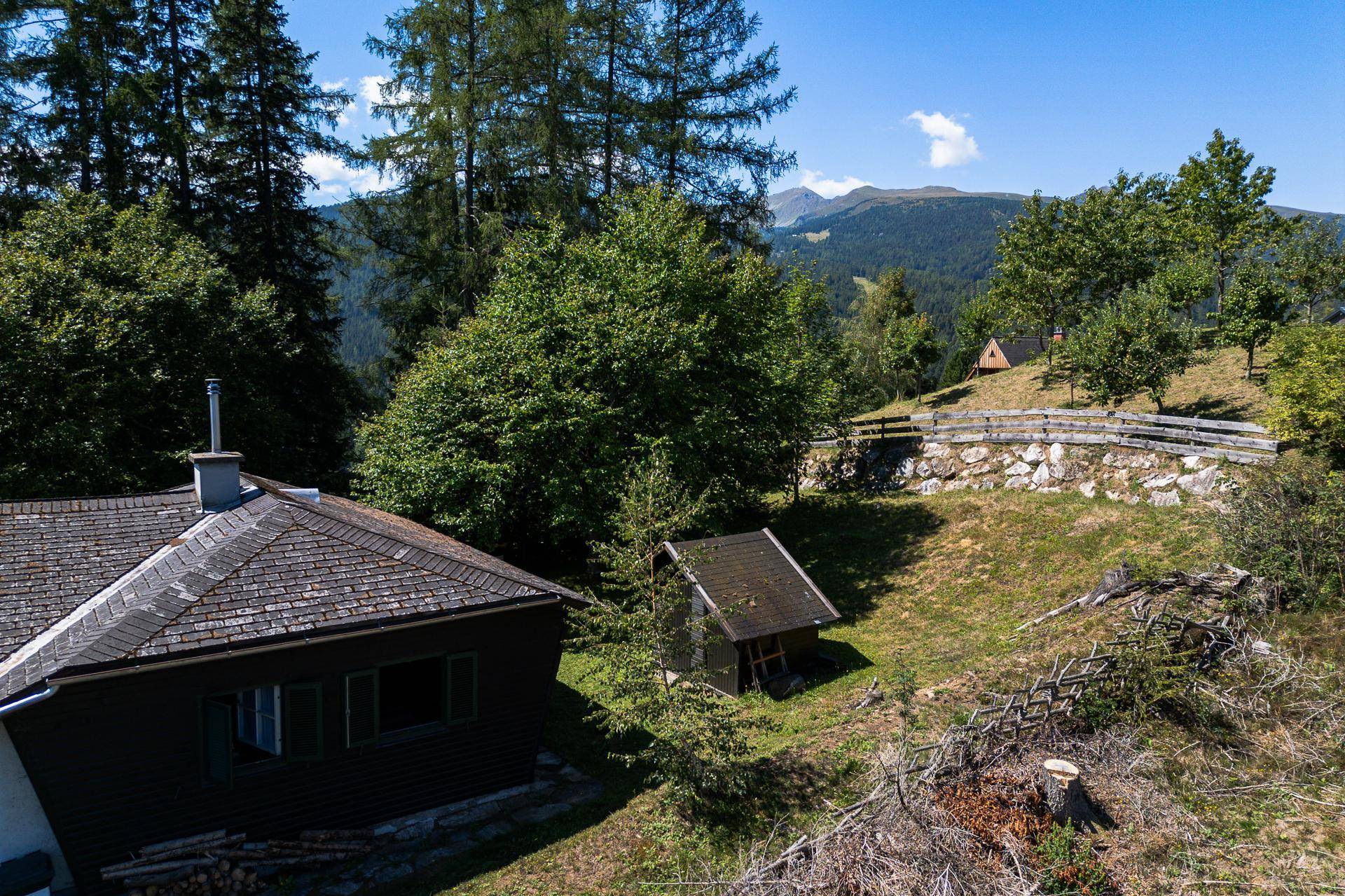 Das Haus mit Holzdach und grünen Fensterläden, eingebettet in eine Berglandschaft.